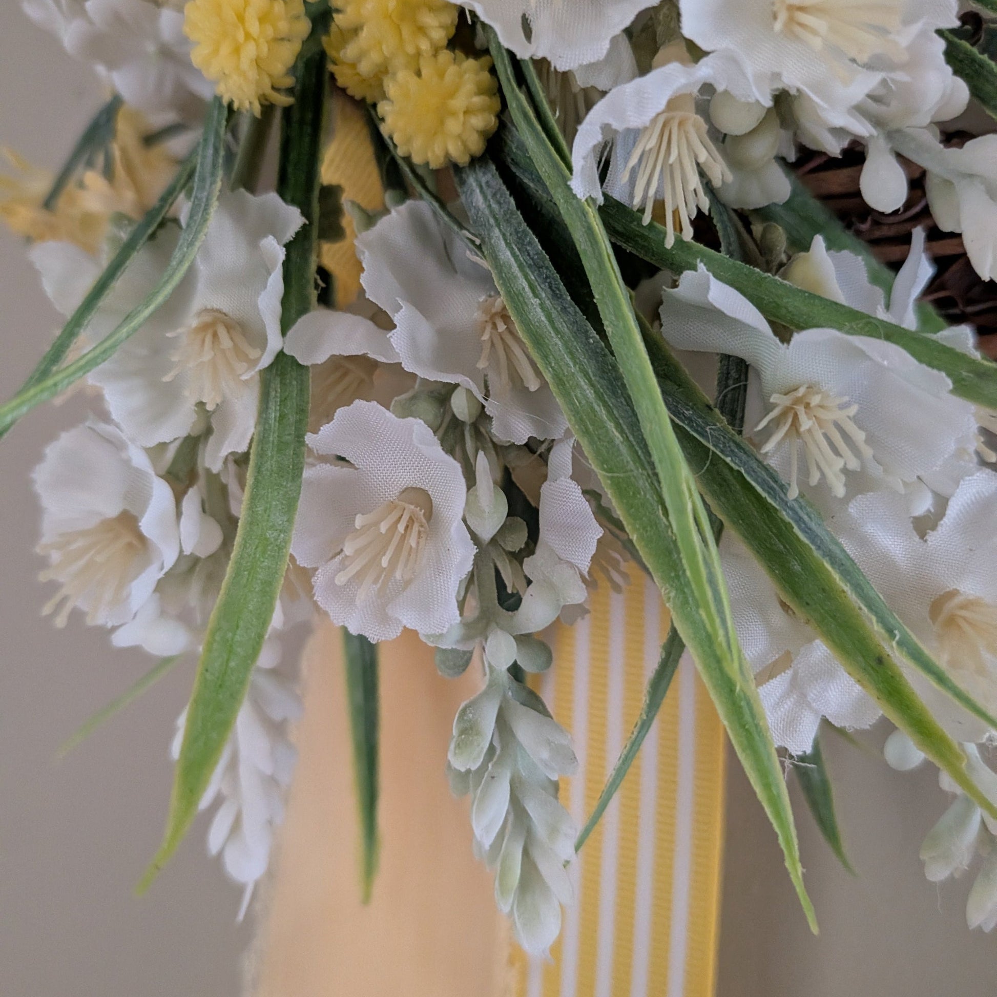 Close up detail of lemon and white faux flowers and candy striped yellow ribbon and lemon chiffon ribbon