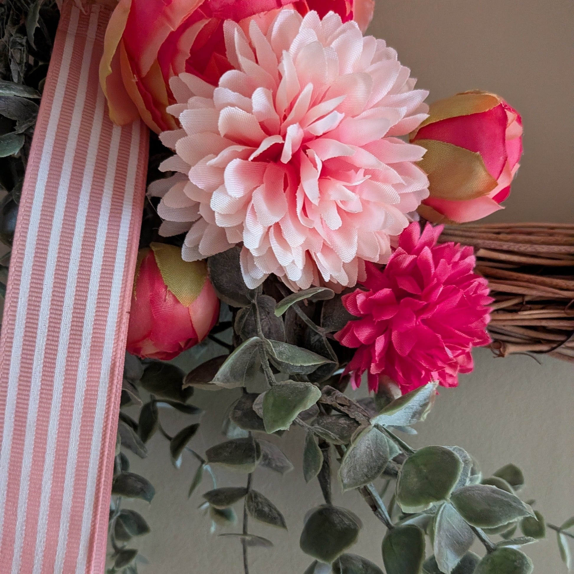 A close up of the Rhubarb & Custard wreath showing the pink candy stripe ribbon and faux florals