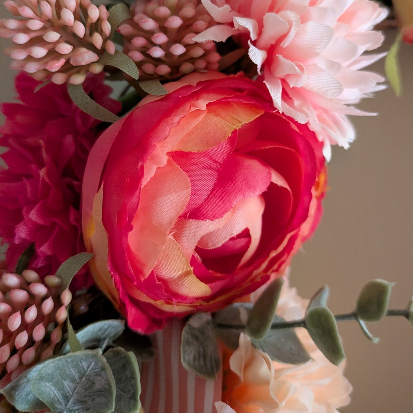 close up of Rhubarb & Custard wreath 20cm - showing details of faux Ranniculus, other pink florals and pink candy stripe ribbon 