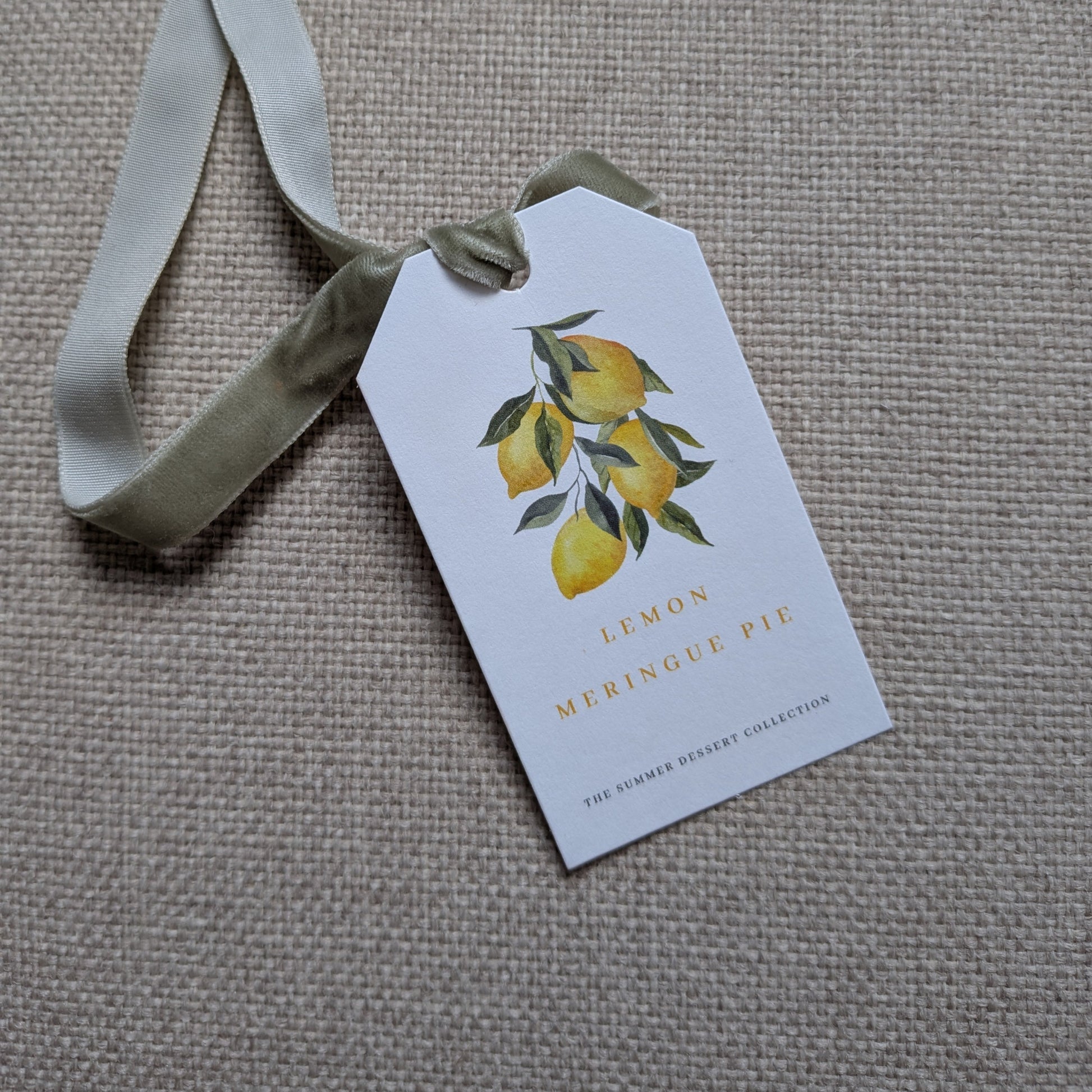 Close up of the front of the Lemon Meringue Pie tag with a sage green velvet ribbon
