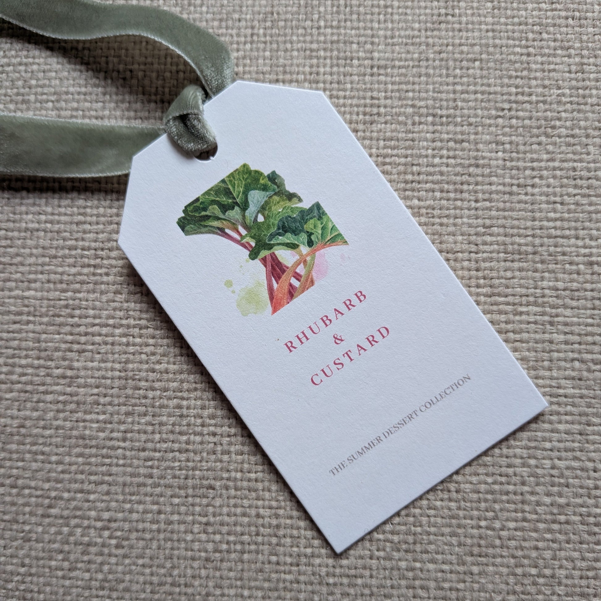 close up of the front of the Rhubarb & Custard tag with a sage green velvet ribbon