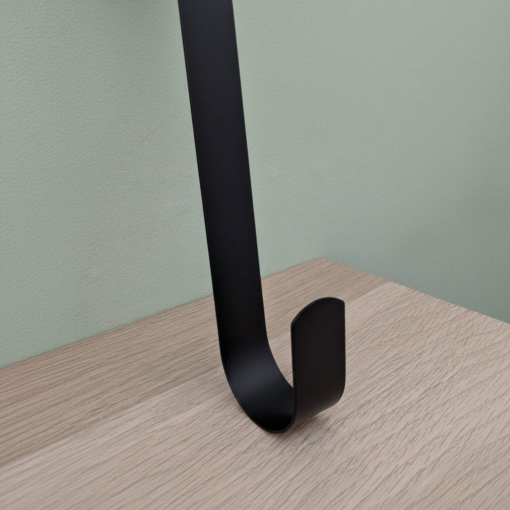 Close-up of black metal wreath hanger hook detail showing curved end